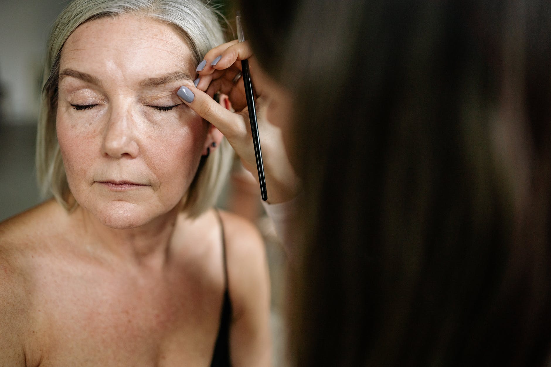 an elderly woman having her makeup done