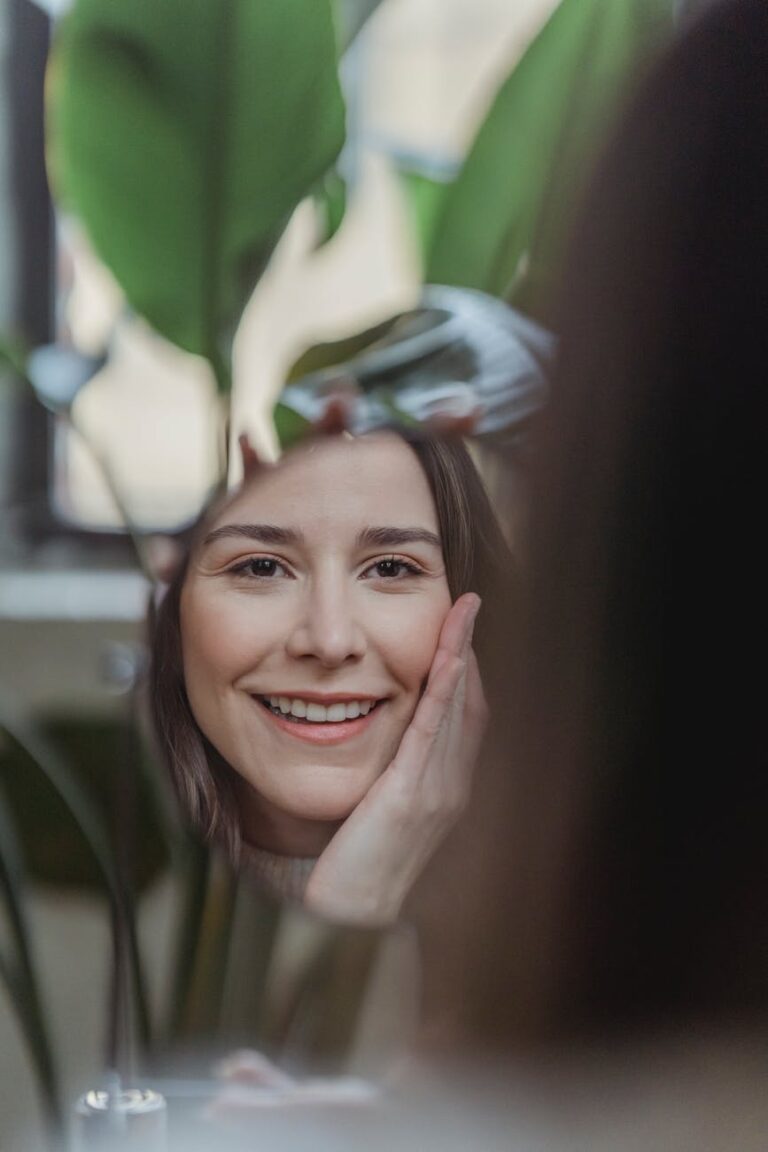 confident smiling young woman touching face and looking in mirror