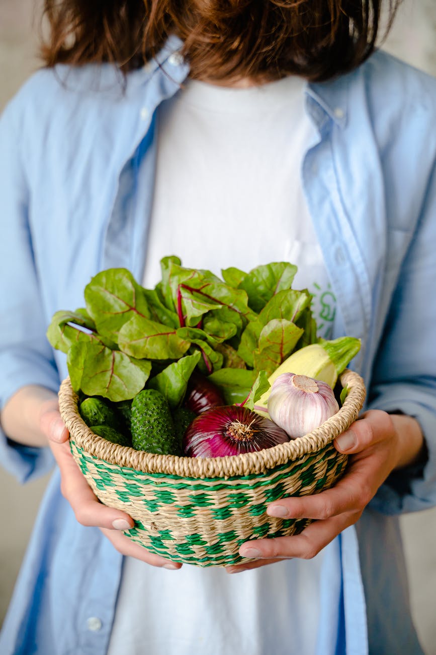 woman holding a basket with vegetables