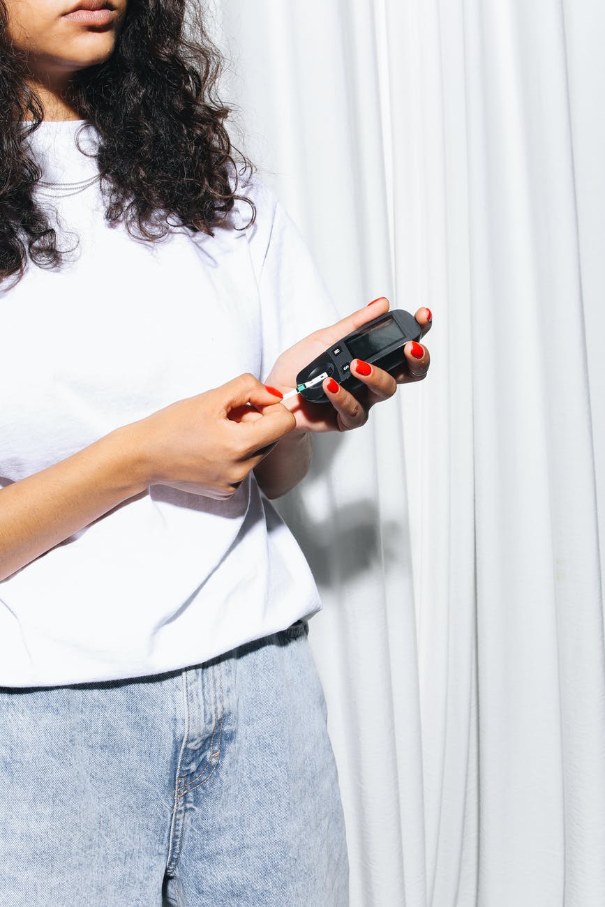 woman in white shirt and blue denim jeans holding black smartphone