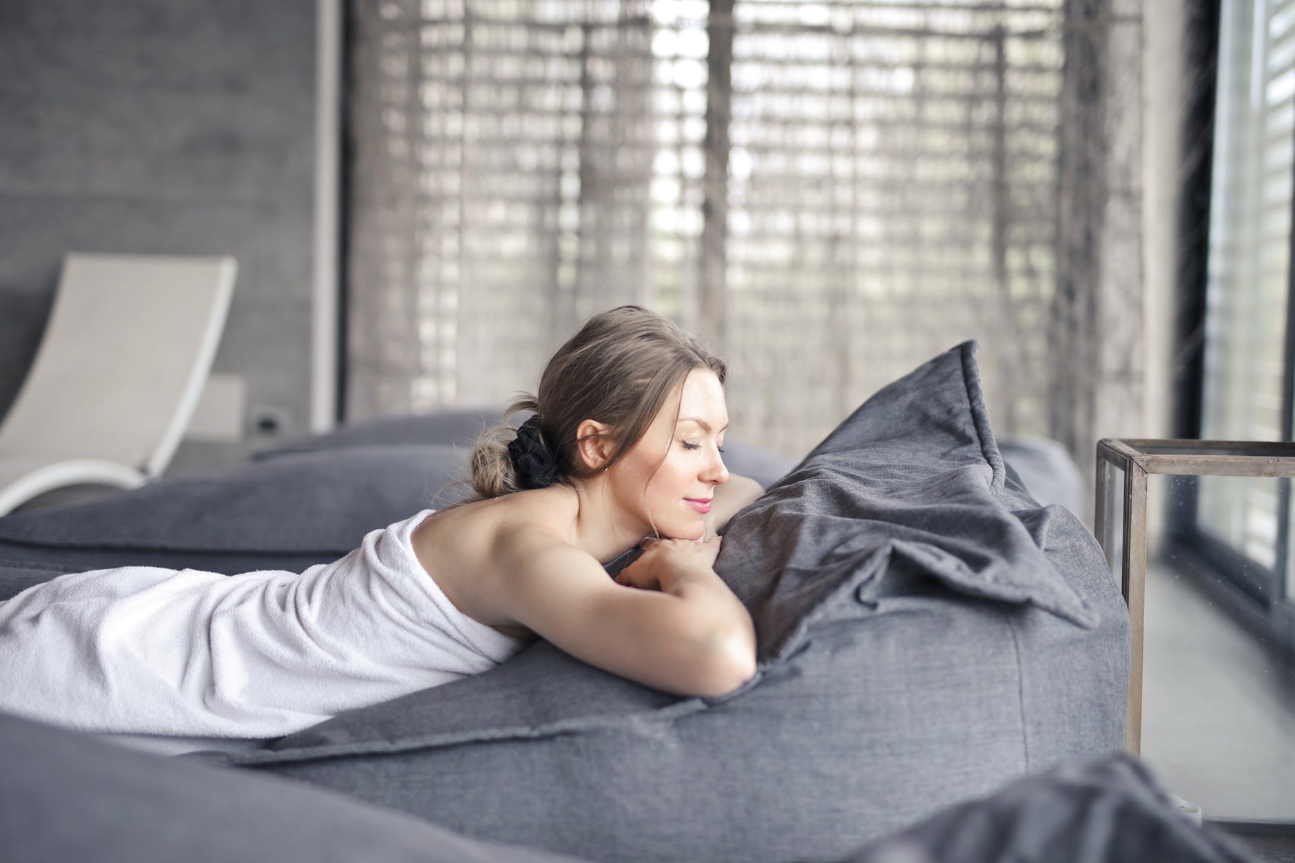 woman in white tank top lying on gray bed introvert spirituality mental health anxiety mindfulness tips introversion peace meditation meditate focus emotions emotional quiet self care relax relaxing